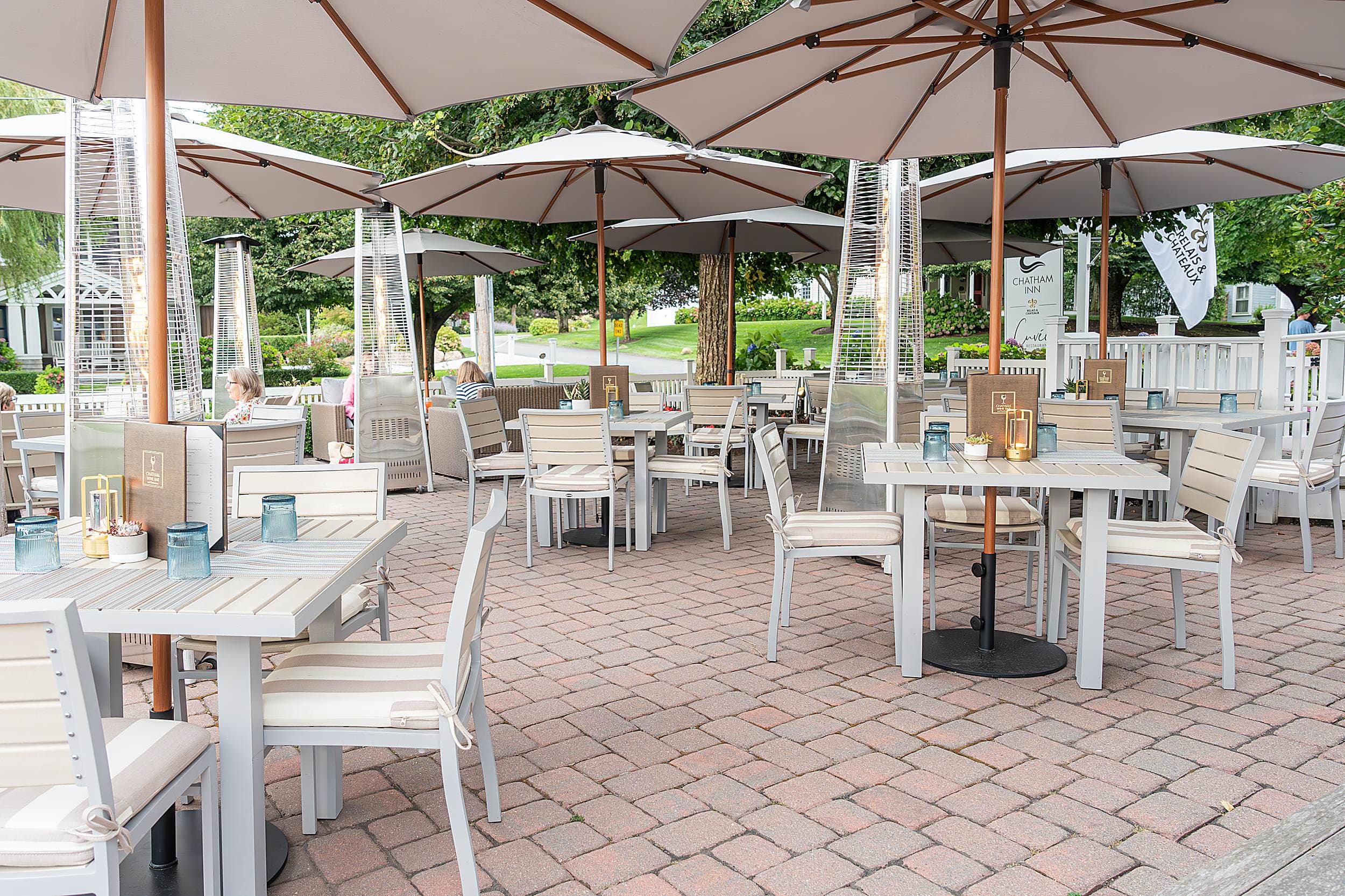 Outdoor seating area with umbrella-shaded tables at Chatham Inn's Cuvée Restaurant.