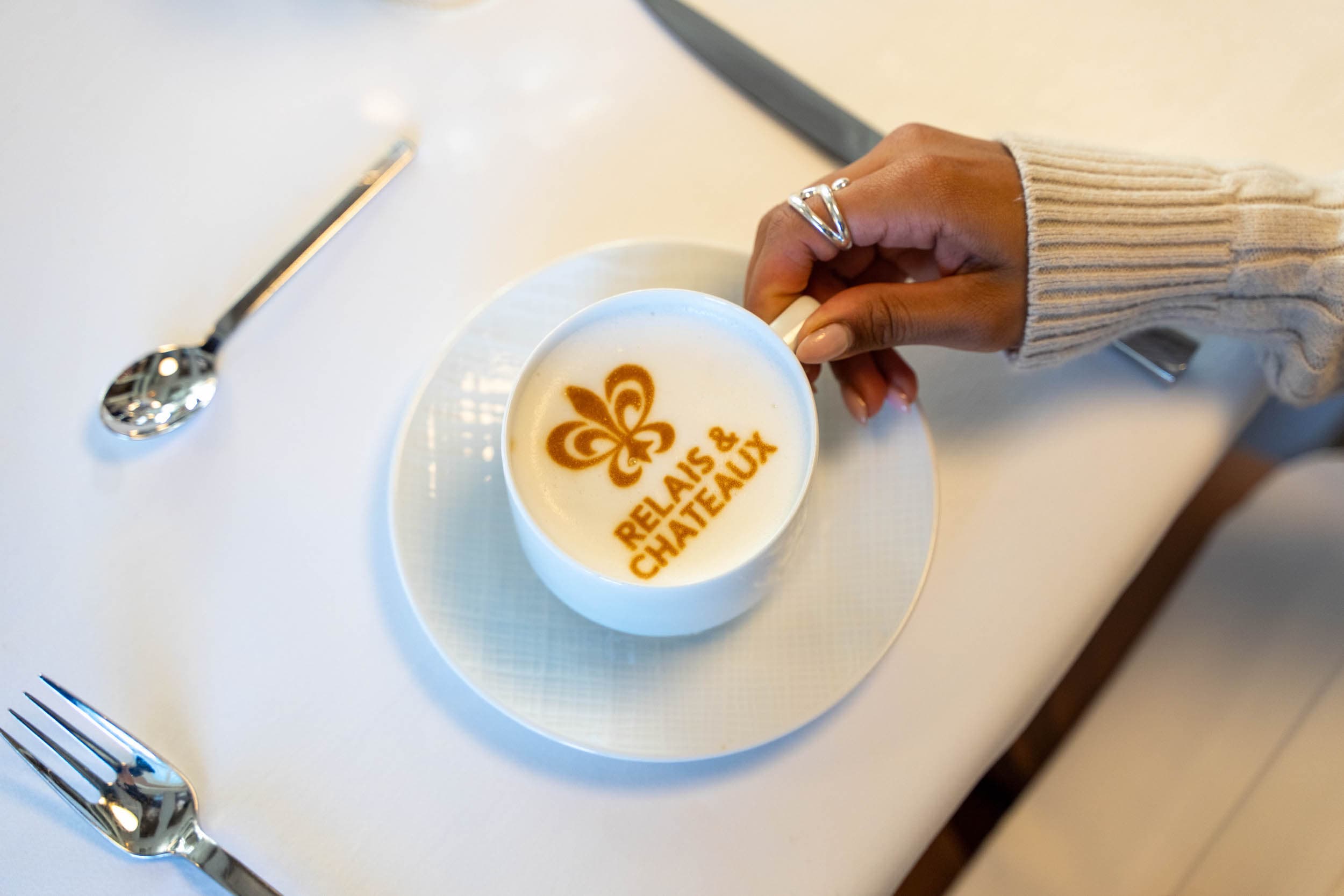 A cappuccino with Relais & chateaux and the logo in the foam of the cappuccino
