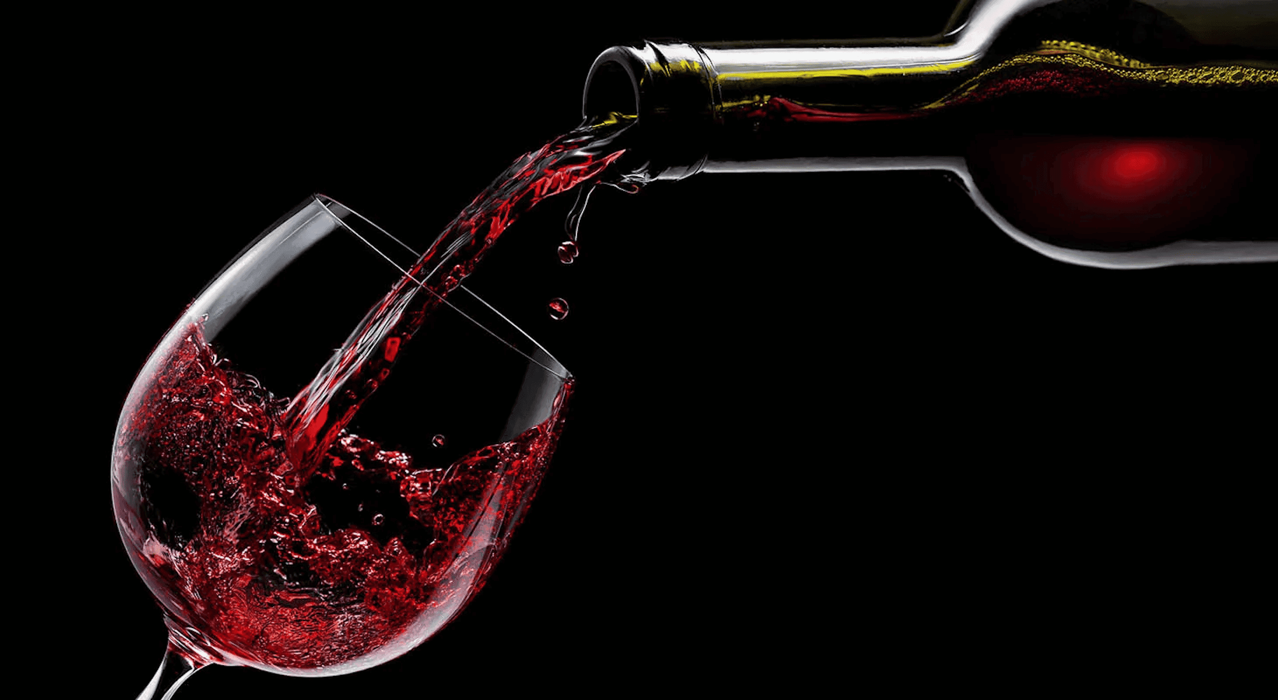 A bottle of red wine being poured into a wine glass