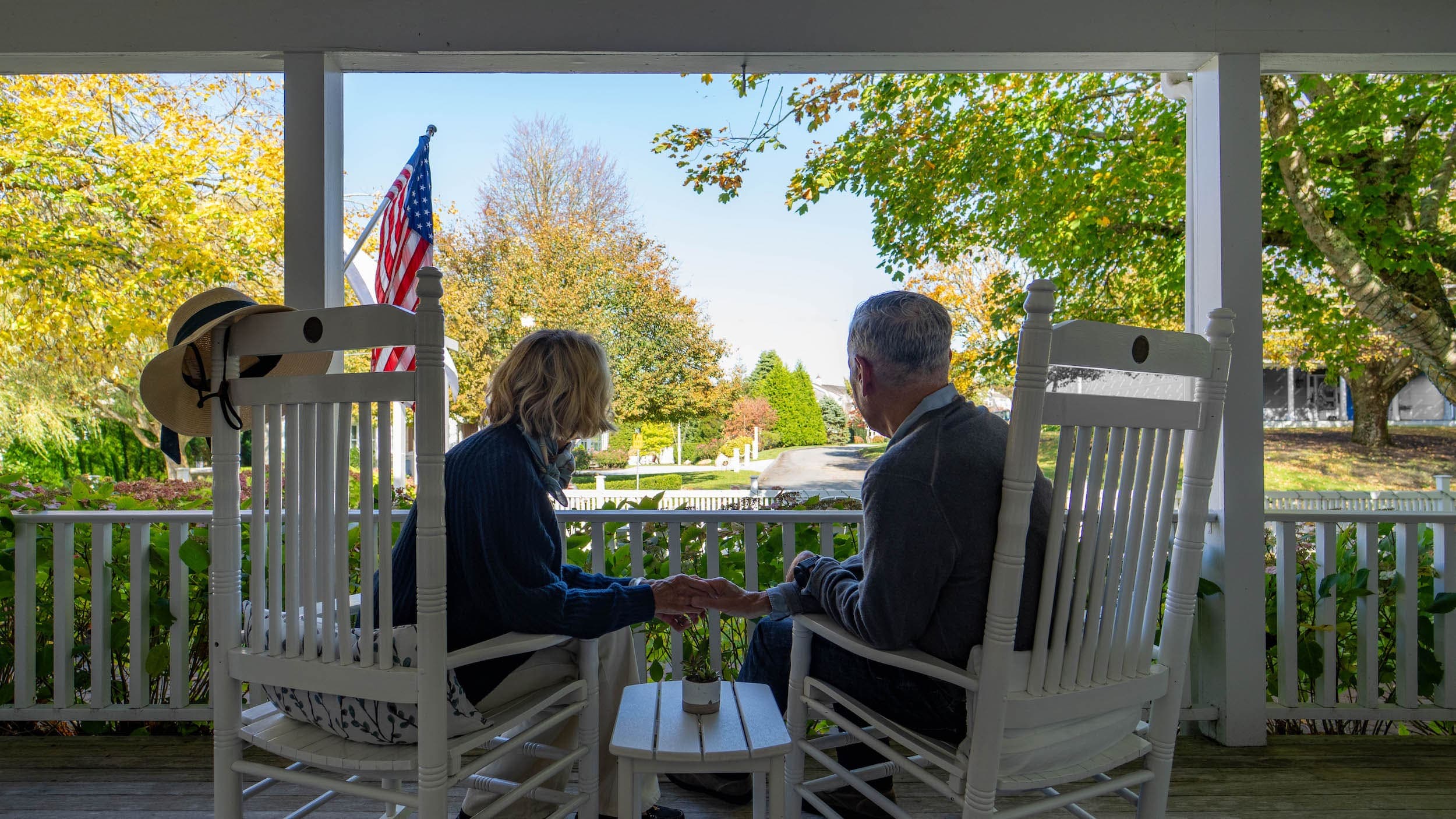 A couple on the from deck holding hands looking out to the street at The Chatham Inn