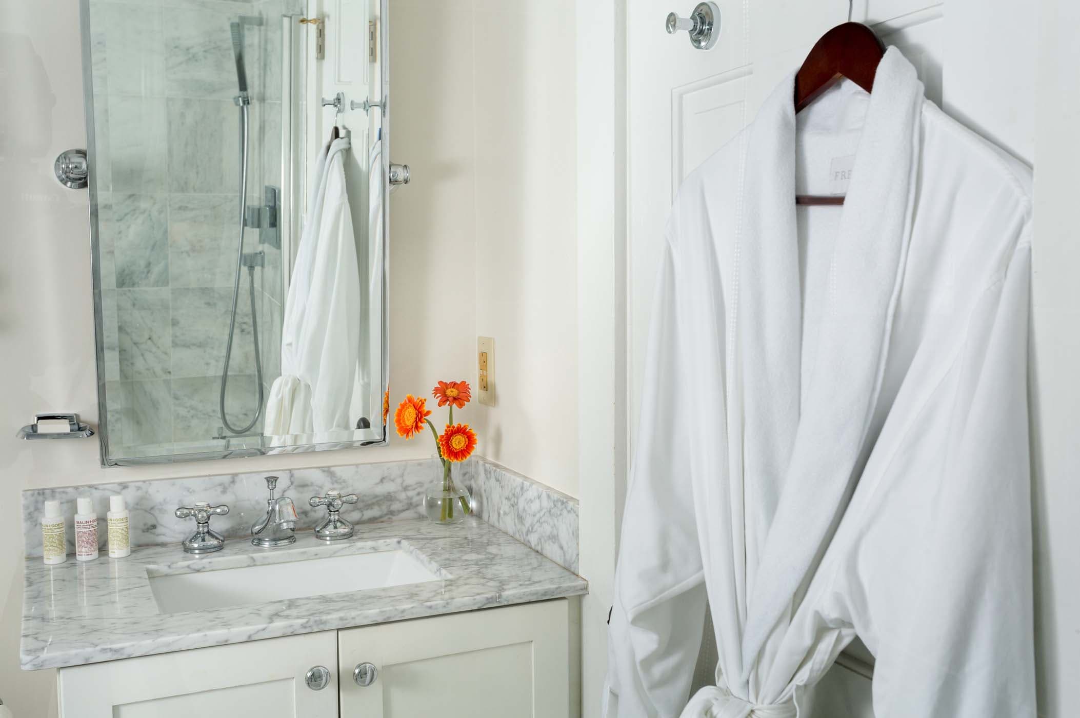 A spacious room 10 bathroom with flowers, and a robe at Chatham Inn