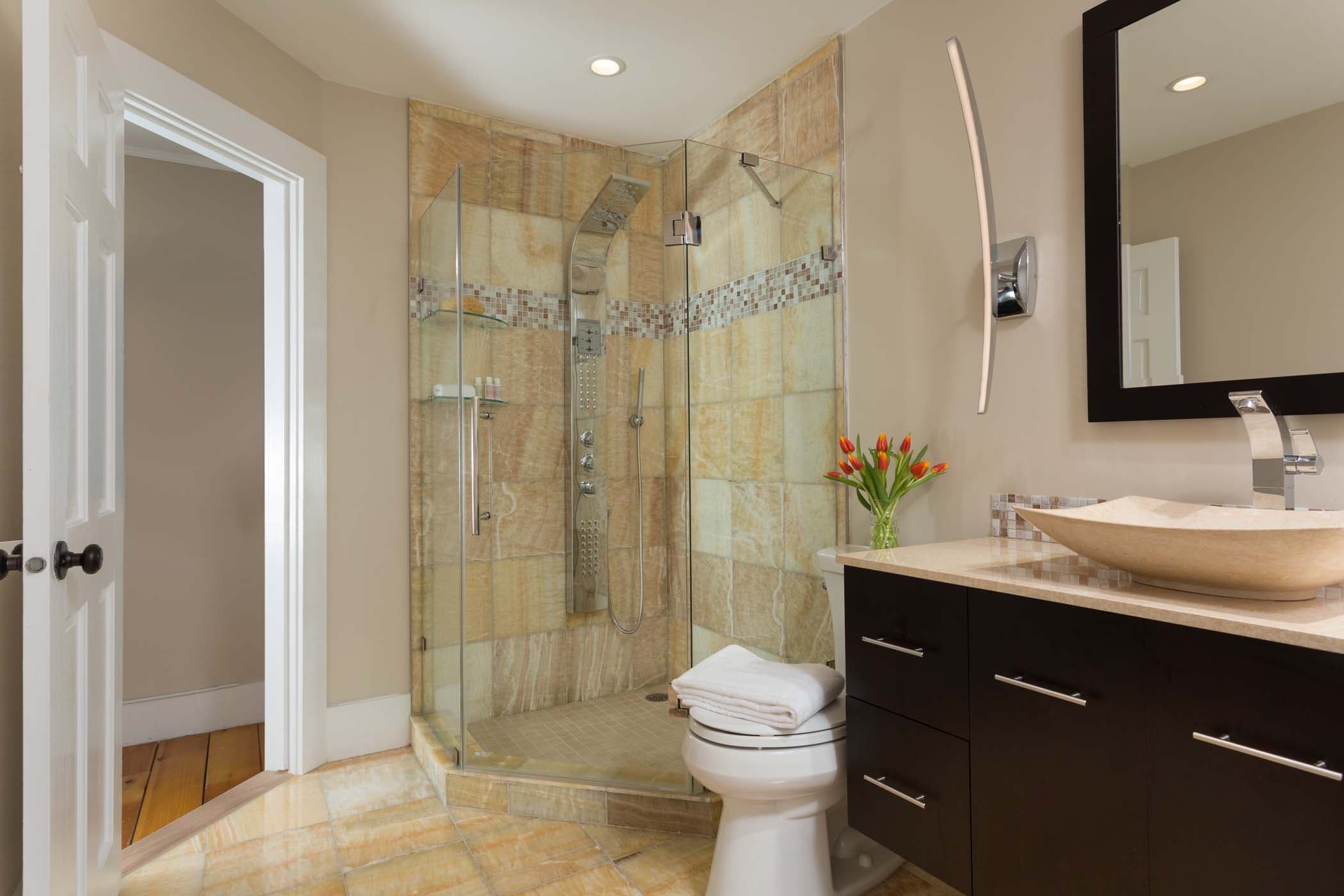 An corner shower and large vanity with a bouquet of tulips in room 11 at Chatham Inn