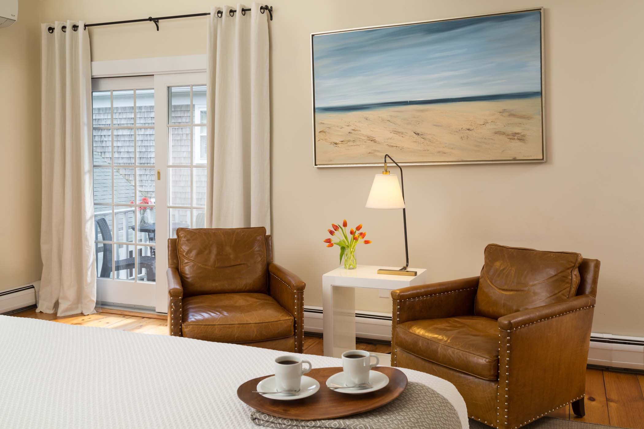 The sitting area beside the bed, with large wall art and two coffees sitting on the bed in Room 12 at Chatham Inn