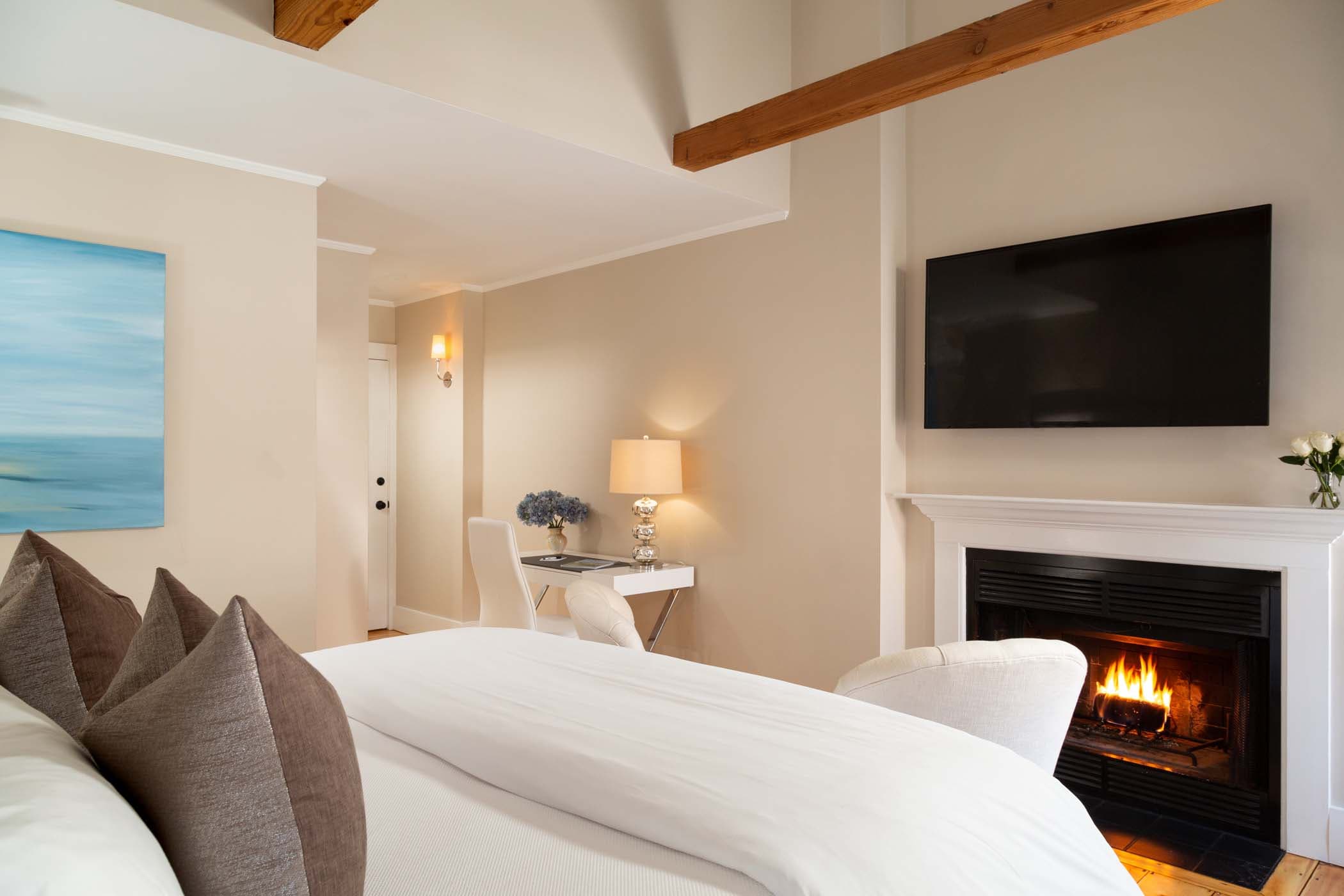 A tv and fireplace at the end of the bed in Room 17 at Chatham Inn