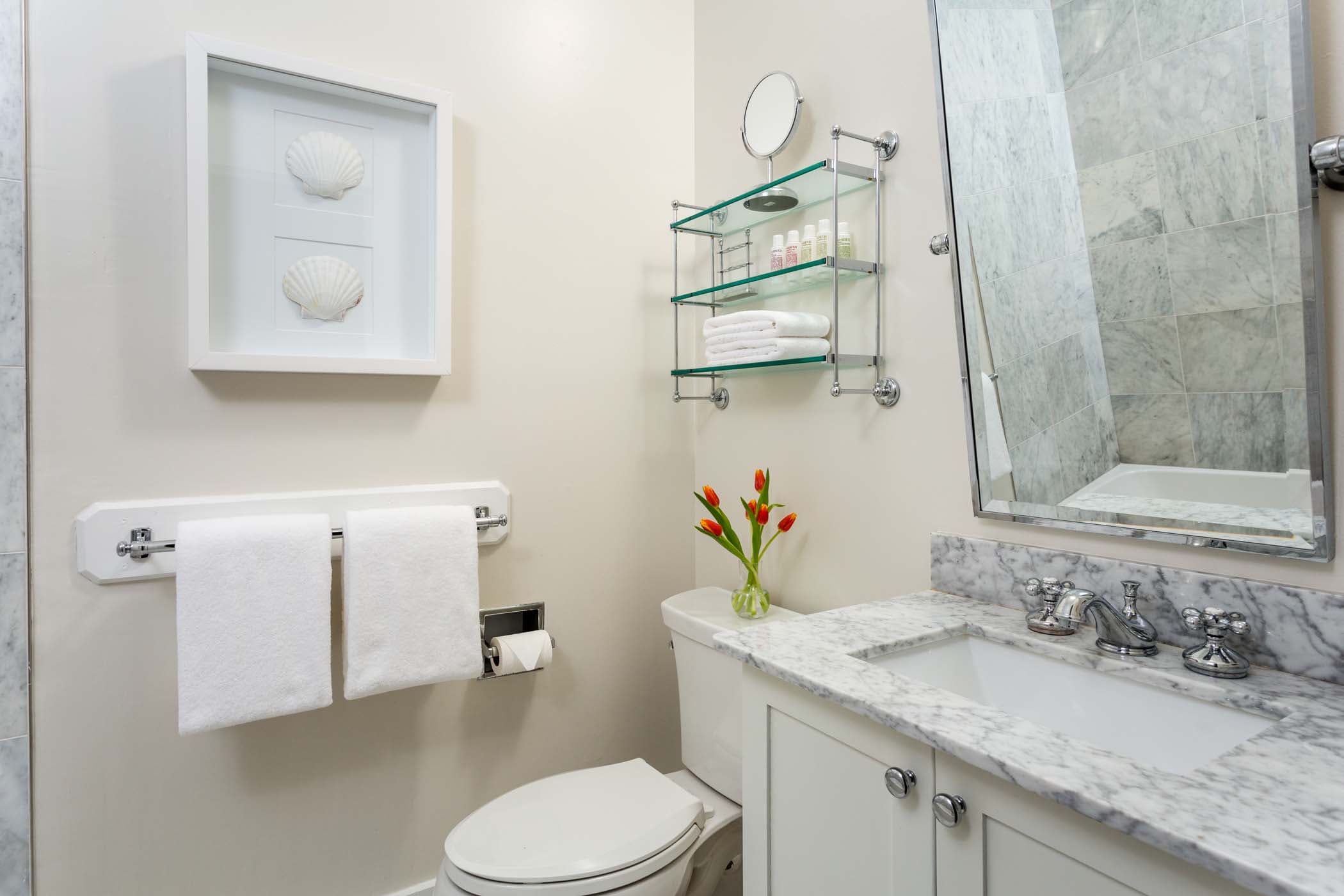 A spacious room 8 bathroom with 6 red tulips and shell art at Chatham Inn