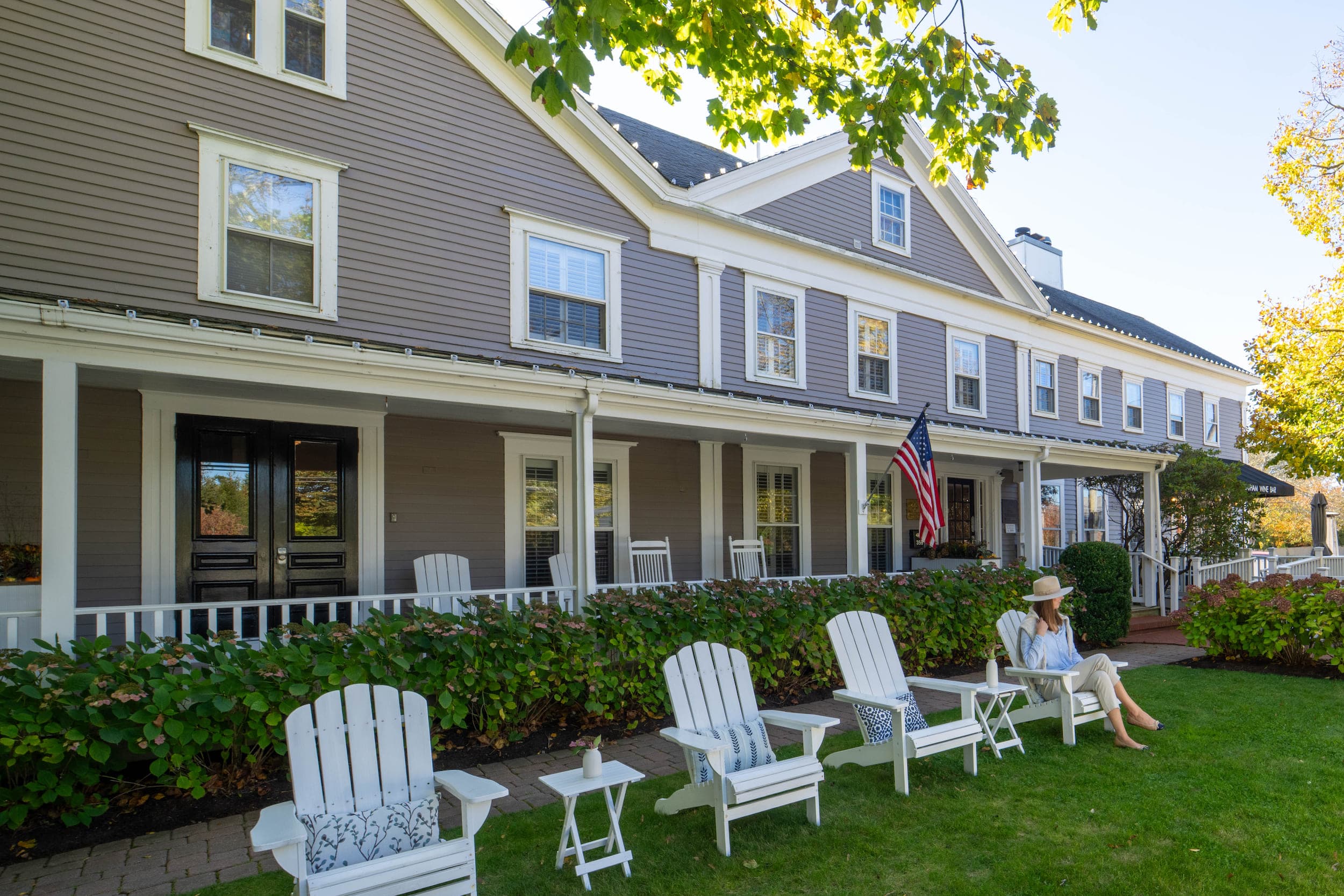 The exterior of the Chatham Inn with a woman sitting in the yard on chair