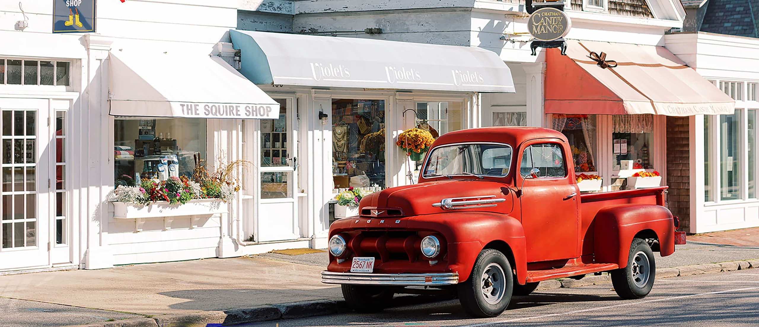 A red vintage truck out front of shops in Cape Cod