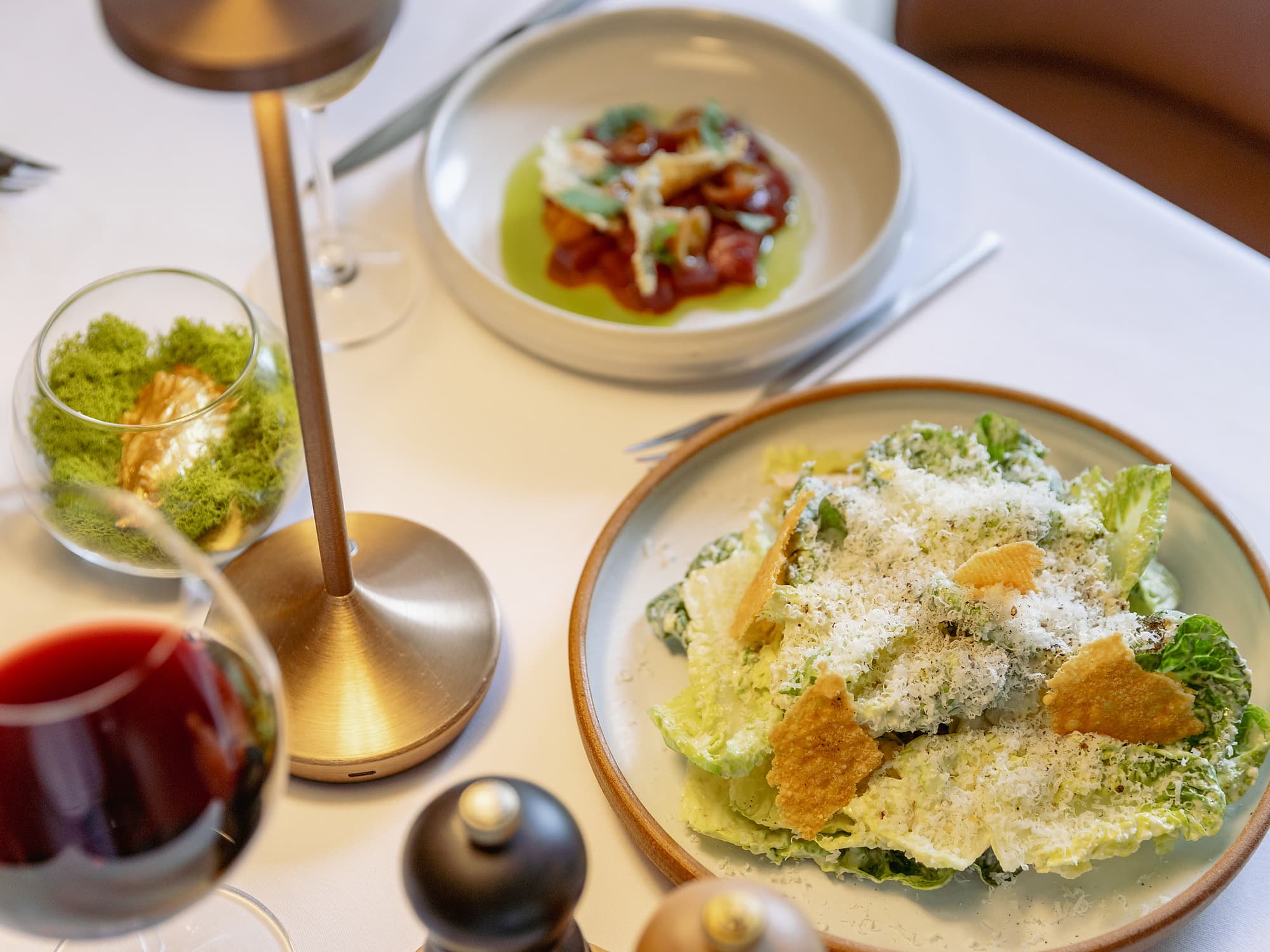 Caesar salad with shaved parmesan and crisp frico beside a tomato and basil first course, paired with red and white wine at the Chatham Inn, a Relais & Châteaux hotel in Chatham, Massachusetts on Cape Cod.