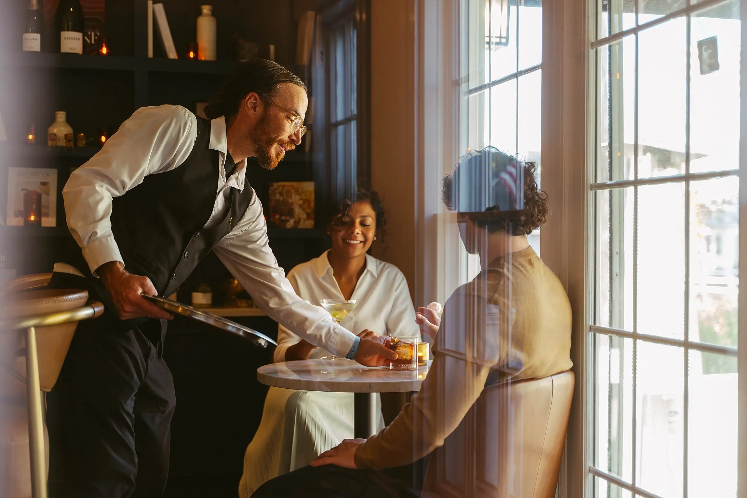 Attentive cocktail service in the sunlit lounge at Chatham Inn, a five-star boutique hotel on Cape Cod, Massachusetts.