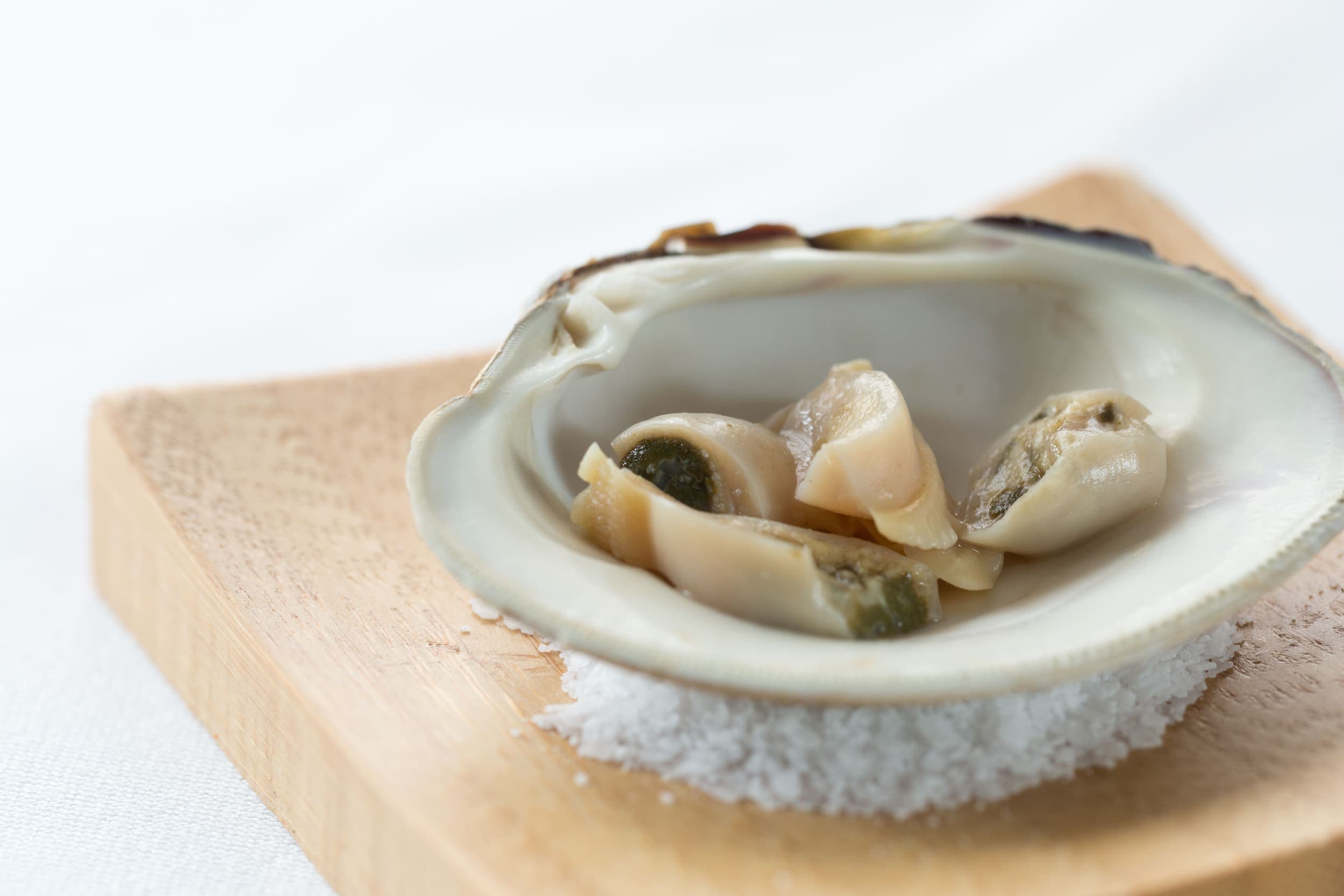 An oyster chopped up in an oyster shell on a bed of sea salt